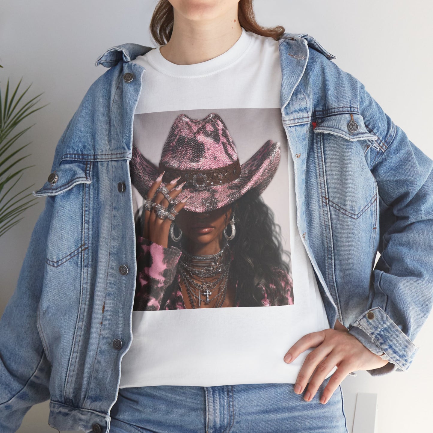 Person wearing a denim jacket over a white t-shirt with a graphic design of a person in a pink cowboy hat.
